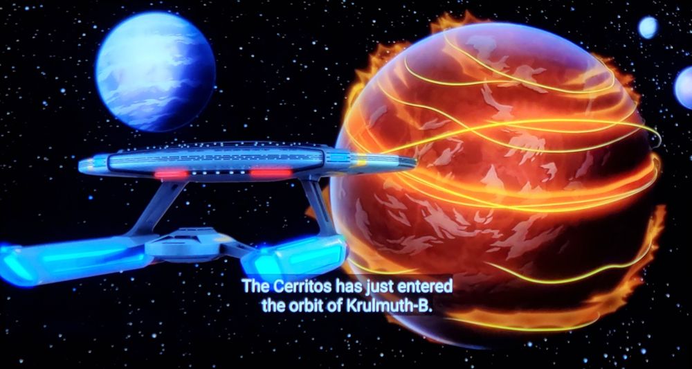 Strange New Worlds/Lower Decks crossover episode. We open in animation, seeing a starship from space approaching a red planet with swirling lines of gold and vapor. Sort of looks like it's got several rings around it but wrapped, not like the disc on Saturn. Another more white planet is pictured and 2 smaller moons in the distance. Closed caption reads, "The Ceritos has just entered the orbit of Krulmuth-B. Home of the Krulmuth-B portal. One of my all time favorite portals."