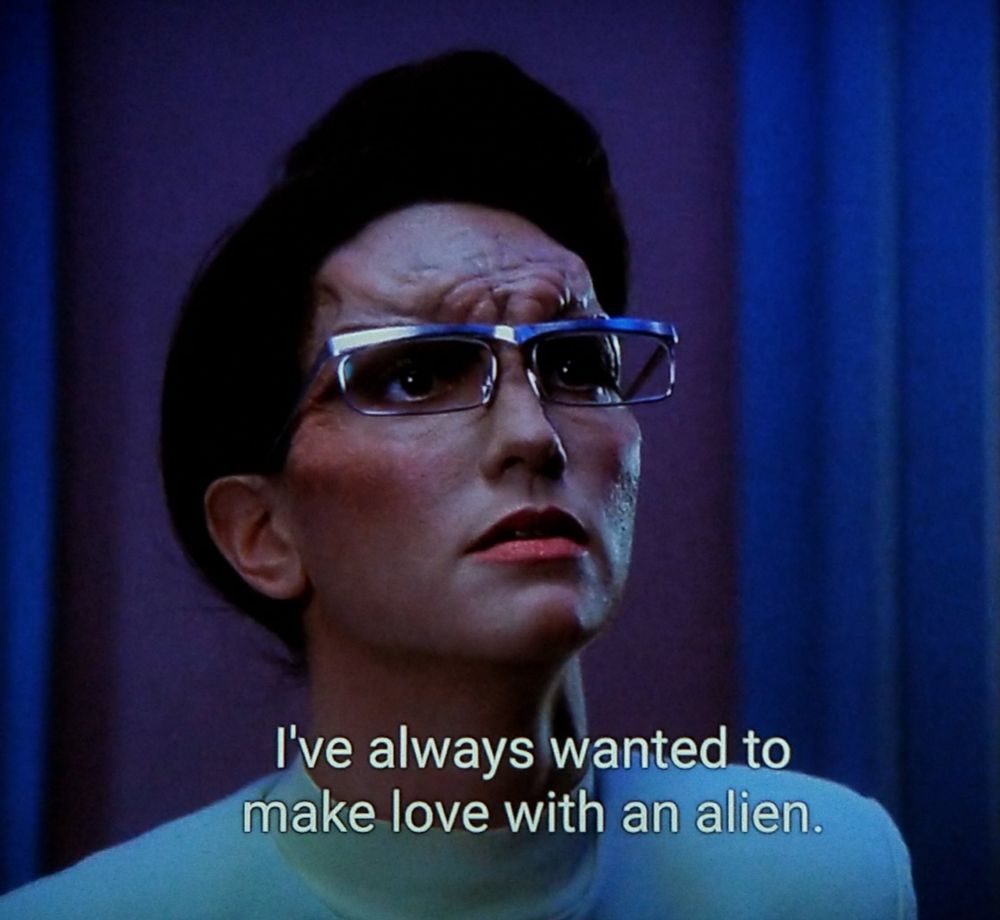 Star Trek The Next Generation scene. Close up on a humanoid alien woman with some ripply looking forehead loaf. She's looking up hopefully and expectantly. Looks a lot like Lilith from Cheers but I'm sure that's just a coincidence. Closed caption reads, "I've always wanted to make love to an alien."