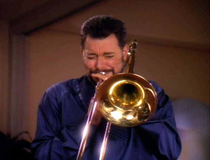Star Trek The Next Generation scene. Ok so it's Riker, in a silky bathrobe, blowing hard on a shiny trombone. Really giving her hell. Just trombonin' like his life depends on it.
