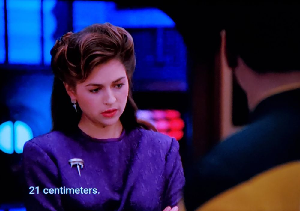 Buckle in everyone it's a 4 picture set. Ok, so the scene displays a convo between Dr Leah Brahms (Dr. B) and Geordi (Geordi), as they are having a chill hang working on engineering stuff. Picture one is focused on Dr B who is looking down and thinking hard about something like she's doing math in her head. Closed caption reads, "21 centimeters." 
Picture two, Dr B is now looking up with a big surprised smile, like she just solved a riddle and is proud of herself. Caption reads, "Oh..."
Picture three is still Dr B talking but is now focused on Geordi who looks like a proud dad watching his son do a good job at sports or something, caption reads, "Oh, that's good, Commander." Picture four is back on Dr B, now smiling and looking like a TV commercial mom who's so proud of the peanut butter she chose for her growing family. Closed caption reads, "That's very good."