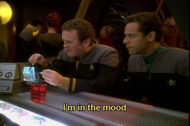 Star Trek Deep Space Nine scene. Chief Miles Edward O'Brien, who built the hospital he was born in, and Dr. Bashir are sitting at a bar with bar patrons in the background. O'Brien, who once smoked a cigarette and cigarettes have been obsessed with him ever since, is squinting and concentrating hard while tinkering with some tools and a project. Bashir on the other hand is just being a pretty boi sitting next to him. Closed caption reads, "I'm in the mood"