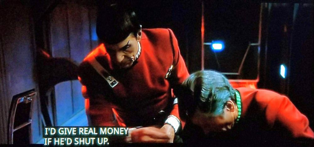 Scene from Star Trek: The Undiscovered Country. 
We're on ship, it's dark, and we're in some kind of back section where you crawl to work on stuff. Bones is bent over working on said stuff, and Spock is leaning over him, also looking at the stuff Bones is working on. Closed caption reads, "I'd give real money if he'd shut up."