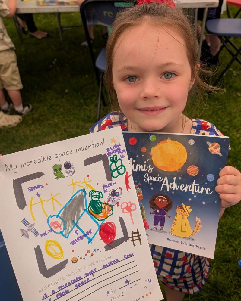Wee girl holds her competition entry form and copy of Mimi's Space Adventure