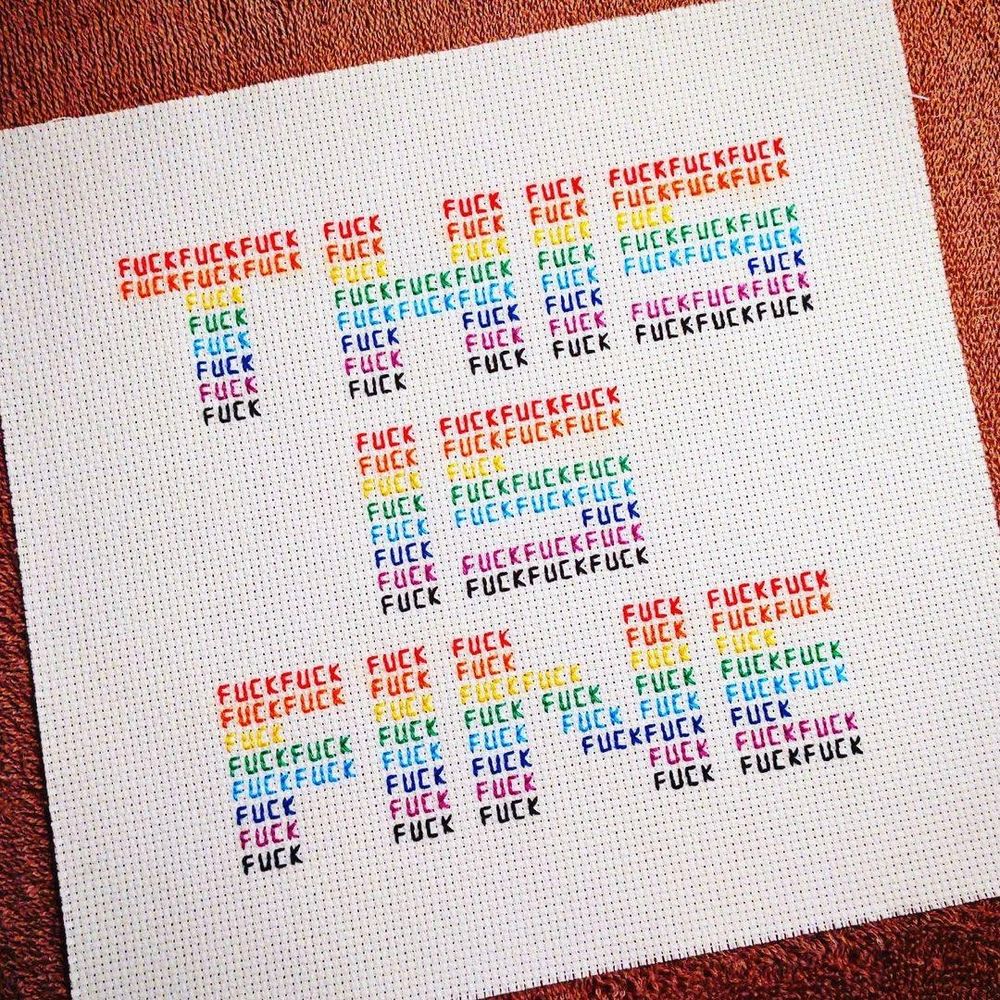 embroidered / cross stitched art that reads "THIS IS FINE" in block letters. The block letters are composed of tiny repeated instances of the word "fuck". The piece is stitched with rainbow threads.