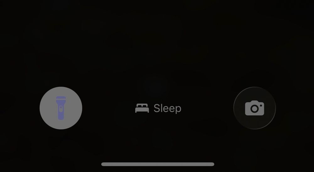 A screenshot of an iPhone Lock Screen with the new Apple glass. The flashlight icon is incredibly difficult to see. Instead of a high contrast color, it is light purple on white. 