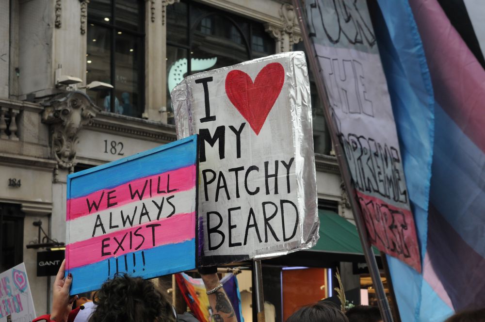 Two signs that read we will always existed and I love my patchy beard