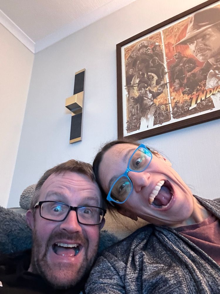 A couple sitting on a couch looking very excited 