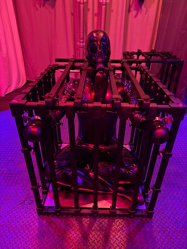 Rubber gimp locked in a cage