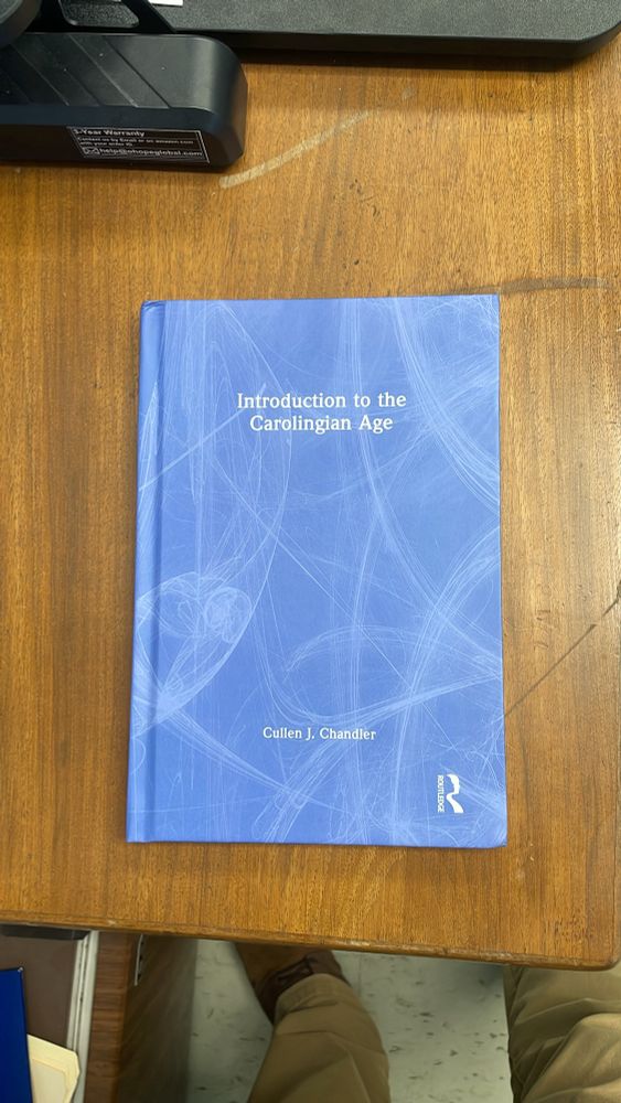 A really boring cover to the hardcover version of “Introduction to the Carolingians Age.” It’s just a periwinkle blue with thin, white arcing lines.