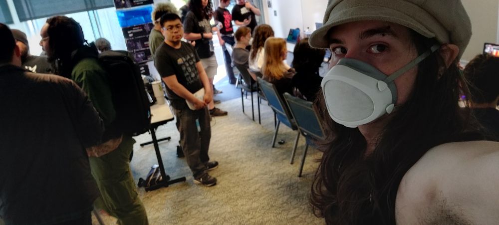 selfie of Joyces in front of several tournament stations with players playing blazblue