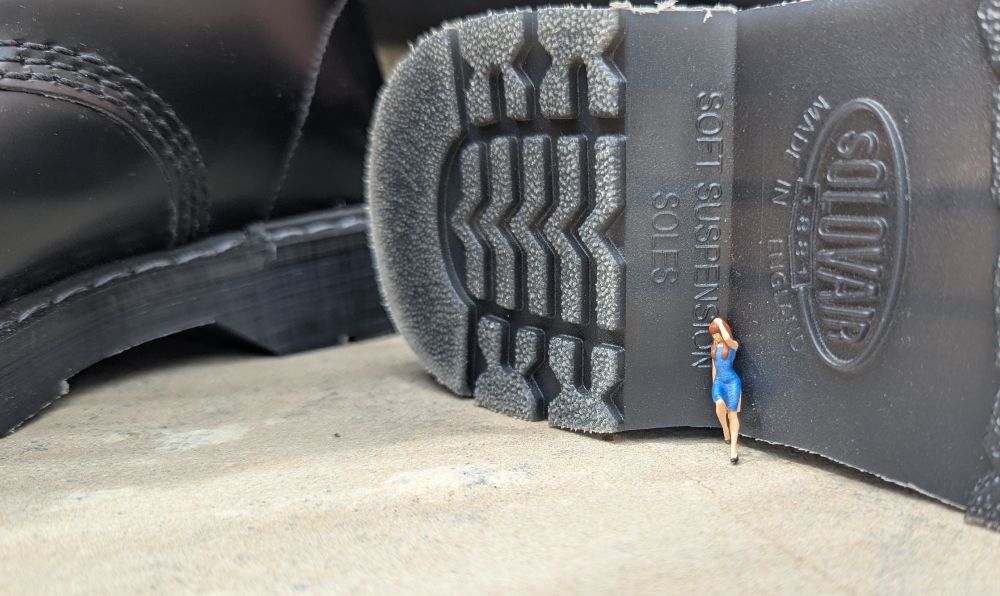 A figurine of a tiny woman in a blue dress leans against the inside of my boot heel.