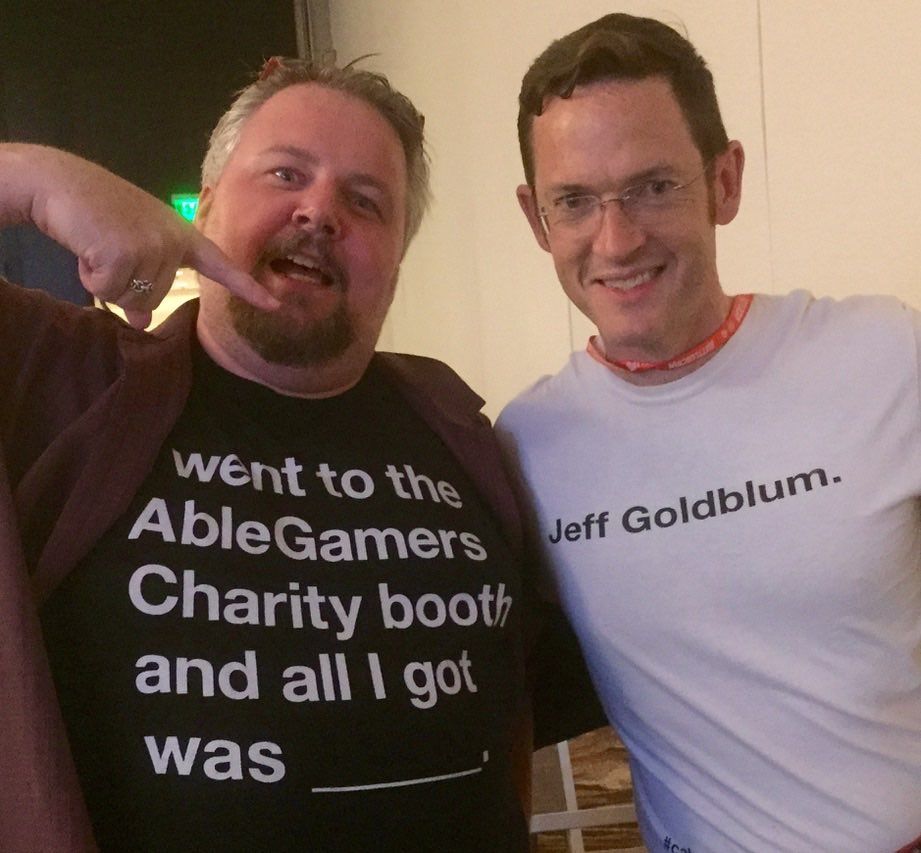 Two pale men wearing gamer-related shirts with text on them. Read together, they say "I went to the AbleGamers Charity booth and all I got was Jeff Goldblum."