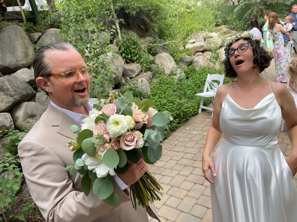 A wedding couple singing together. The groom holds a bright pastel flower bouquet.