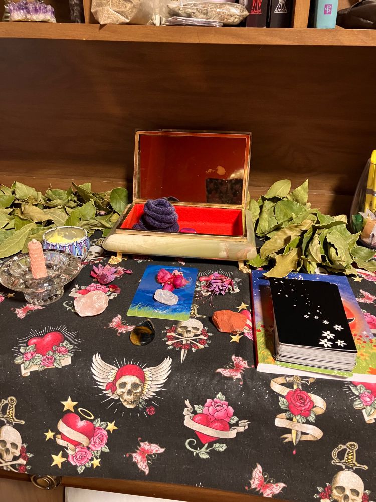 Self love altar with a mirror, crystals, flowers and the wild woman oracle deck.