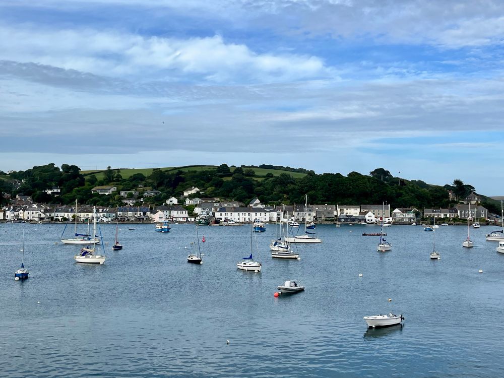 A scenic view of several boats moored in Penryn, Cornwall on a clear day. 