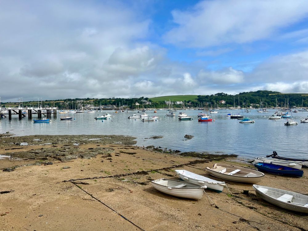 Falmouth harbour with boats resting on exposed sand at low tide and more boats moored on the water beyond. 