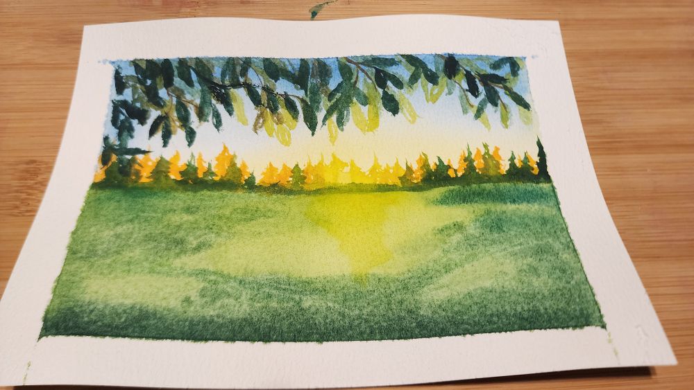 An early watercolor painting of mine of a green field. There is a tree framing the top and a line of far pine trees in front of a very bright Sun. 