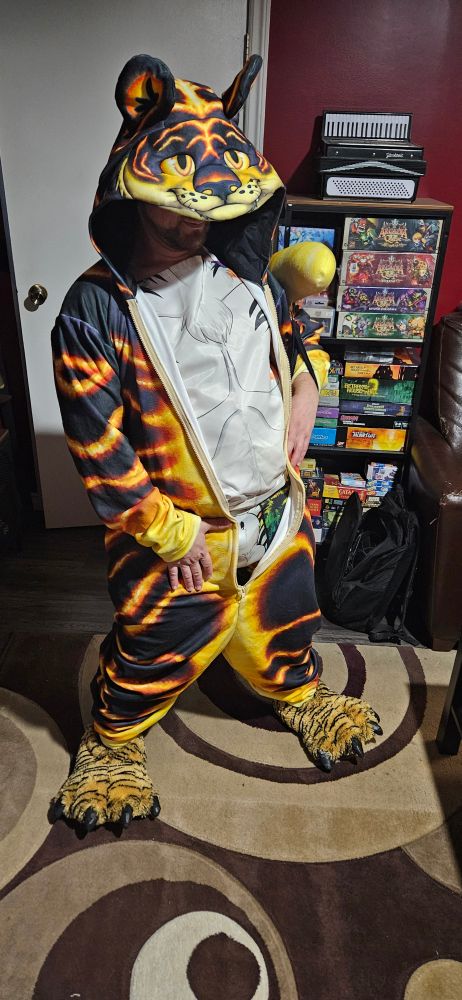 A guy posing suggestive wearing an unzipped tiger kigu revealing a naked tiger apron and underwear with tiger sheath art on the front