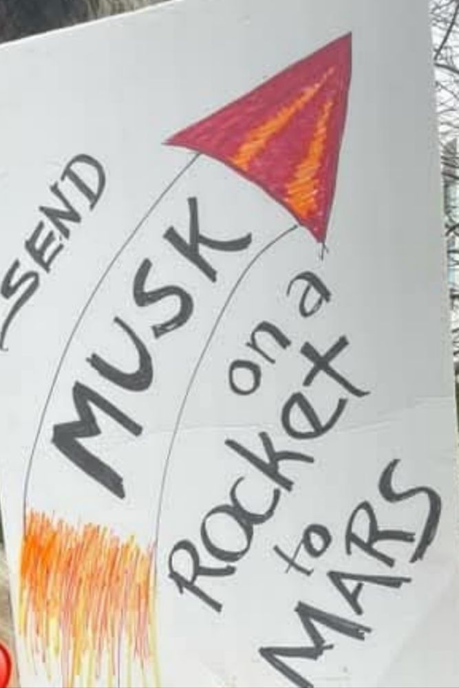 Sign depicts an arrow that is red and orange pointing upward. Arrow appears to be a drawing of a rocket ship. The sign reads, "Send Musk on a rocket to Mars."