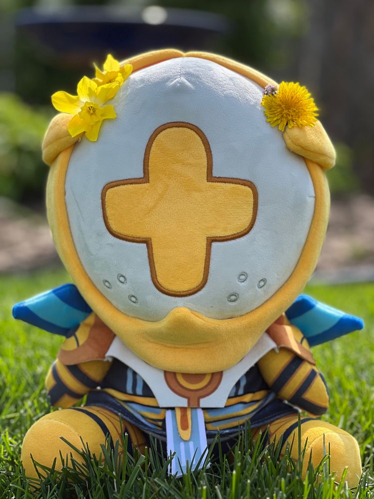 Gabriel ultrakill plush with some yellow flowers stuck under the gold band on top of his head :)