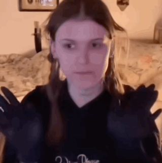 a woman is wearing black gloves and making a face .