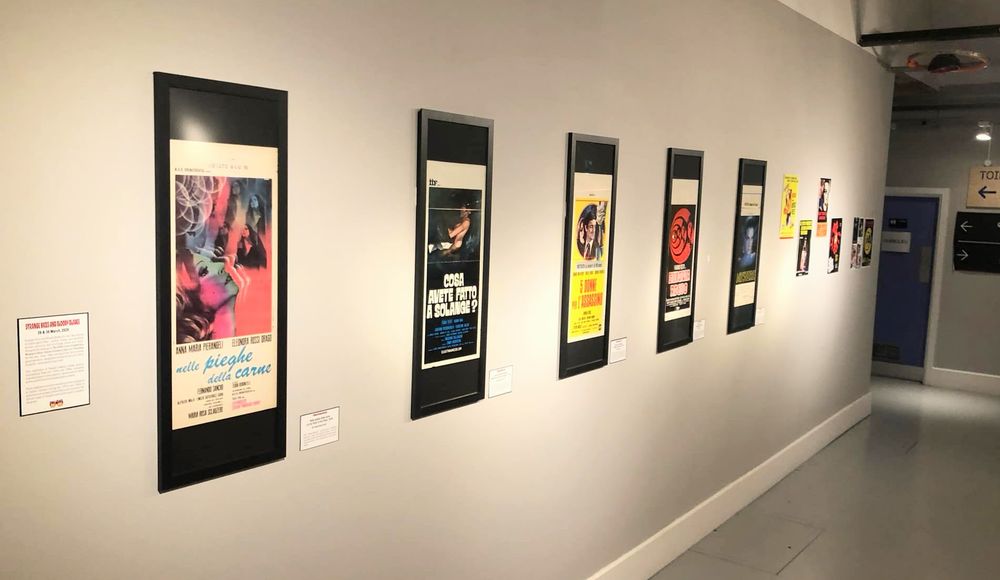 A hallway with an exhibit of colourful Italian 'locandina' movie posters from the 1970s