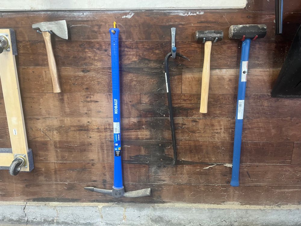 A variety of implements of destruction hanging on a garage wall. 
