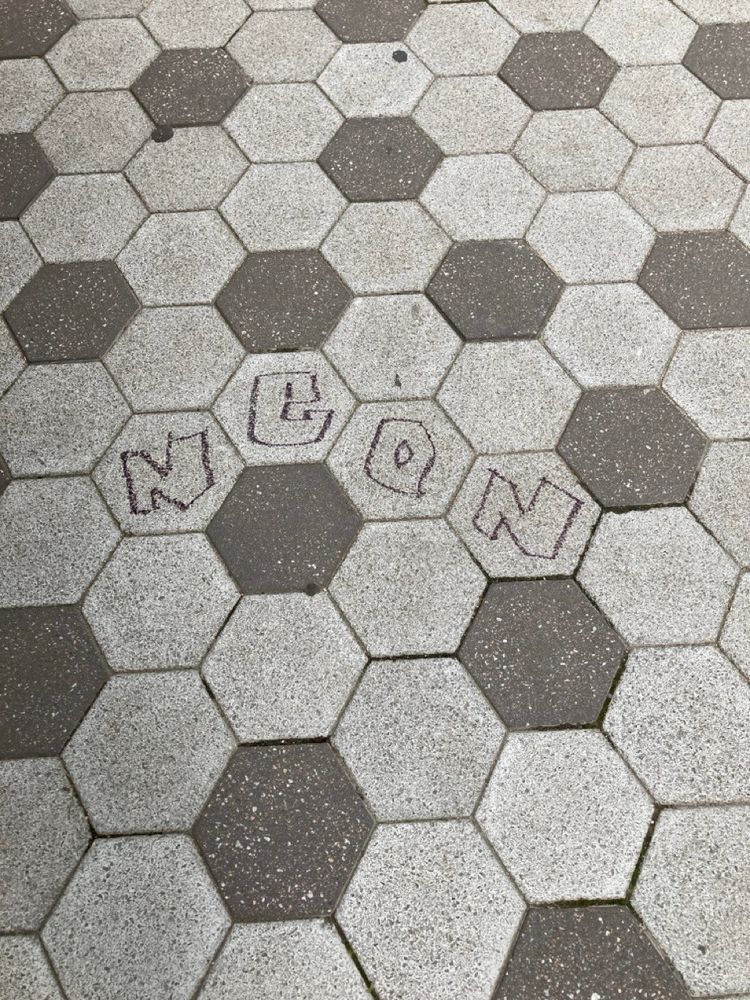 Graffiti drawn on the pavement spelling out the word, "NEON."