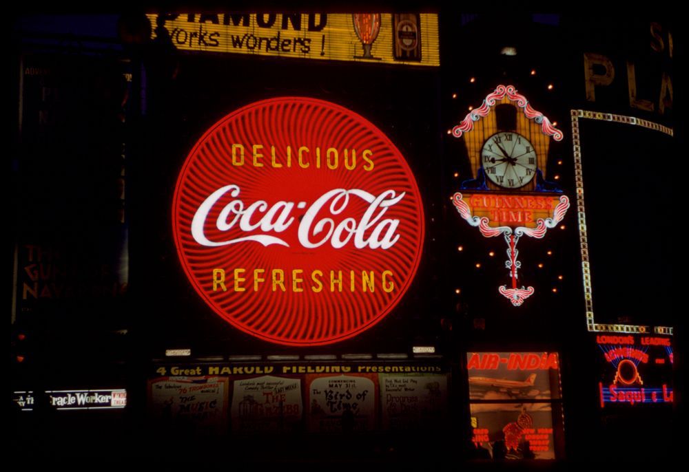 Large Coca-Cola neon sign in red, white, yellow.