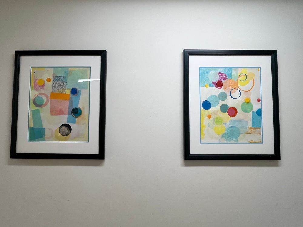 2 tissue paper collage prints hanging on the wall. Collages made with colored tissue paper in pastel colors and in mostly geometric shapes 