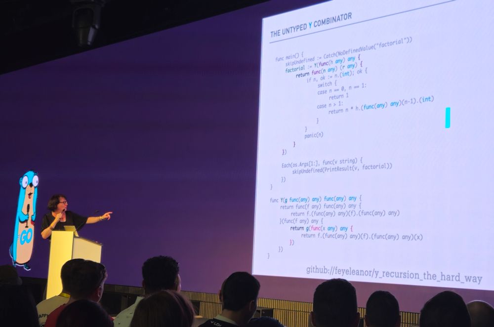 A speaker showing weird functional code in Go and pointing at a screen titled "The untyped Y Conbinator", with a Gopher in the background. 