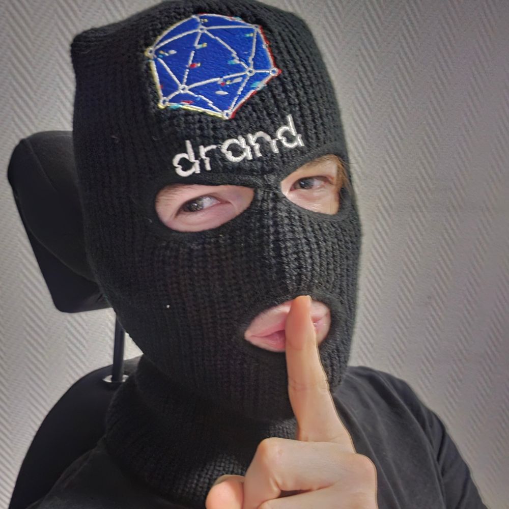 A masked OG dev with the drand logo and brand on his mask, doing a Sssh sign with his finger in front of his mouth. 