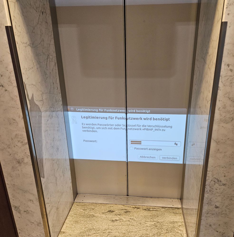 The door of an elevator with a projection of a password prompt pop-up with some German text. 