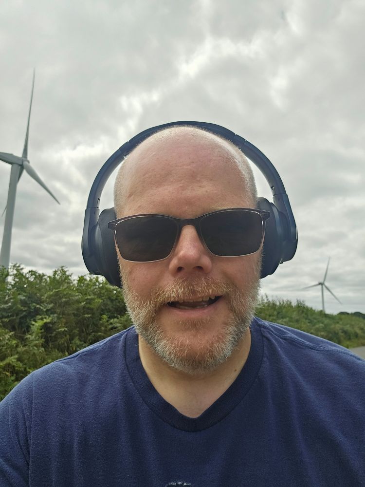 Me looking tired up on Exmoor in front of some trees and wind turbines having just completed a 4 mile training run