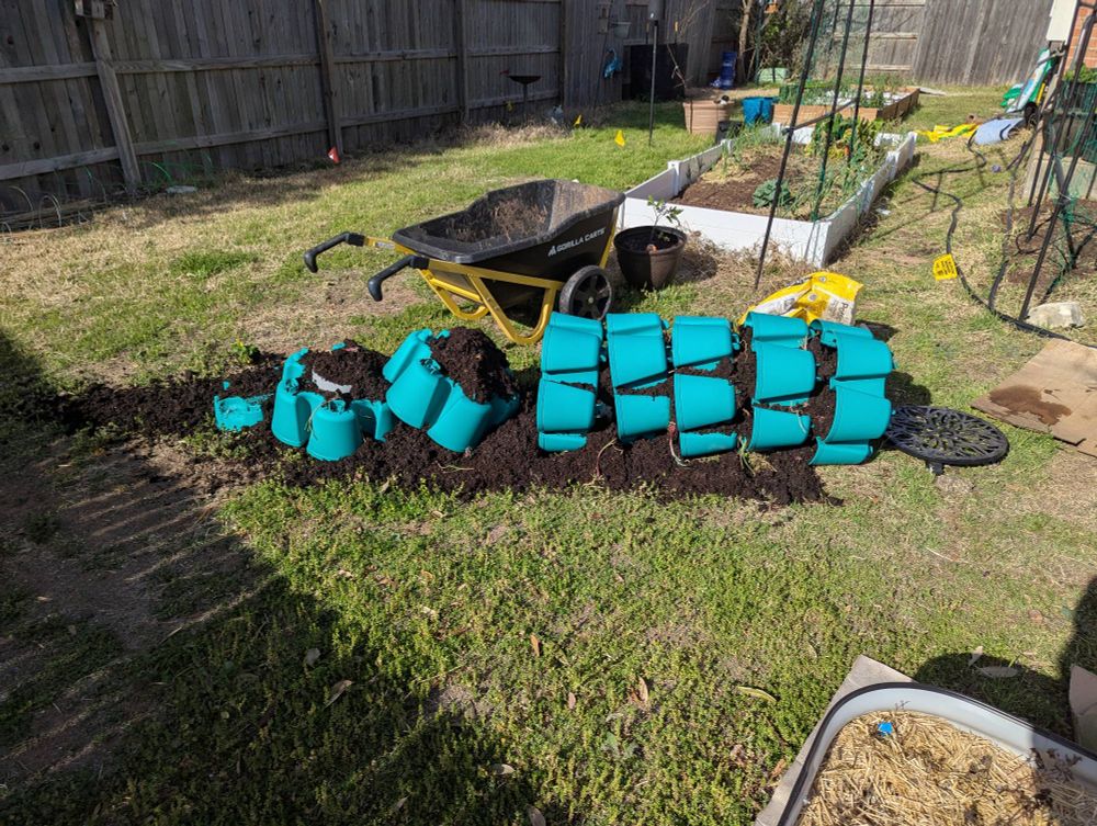 a greenstalk vertical garden planter toppled over with dirt and plants spilling all over the ground. absolutely devastating.