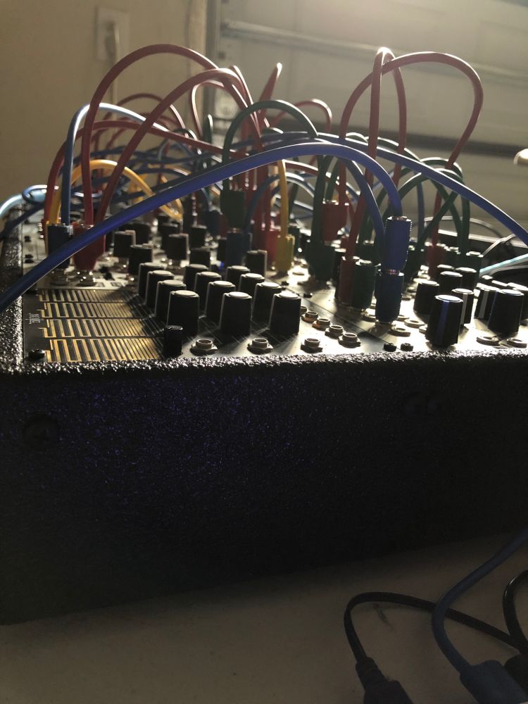 a moderately sized modular synth bristles with wires all over in the early sunlight