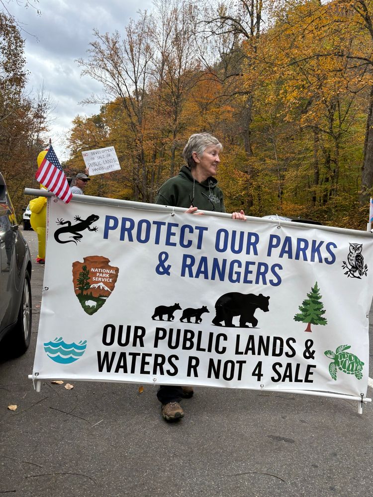 sign that says @ protect our parks and Rangers, with the national park symbol, bears and a tree. and our public lands and waters are not for sale.