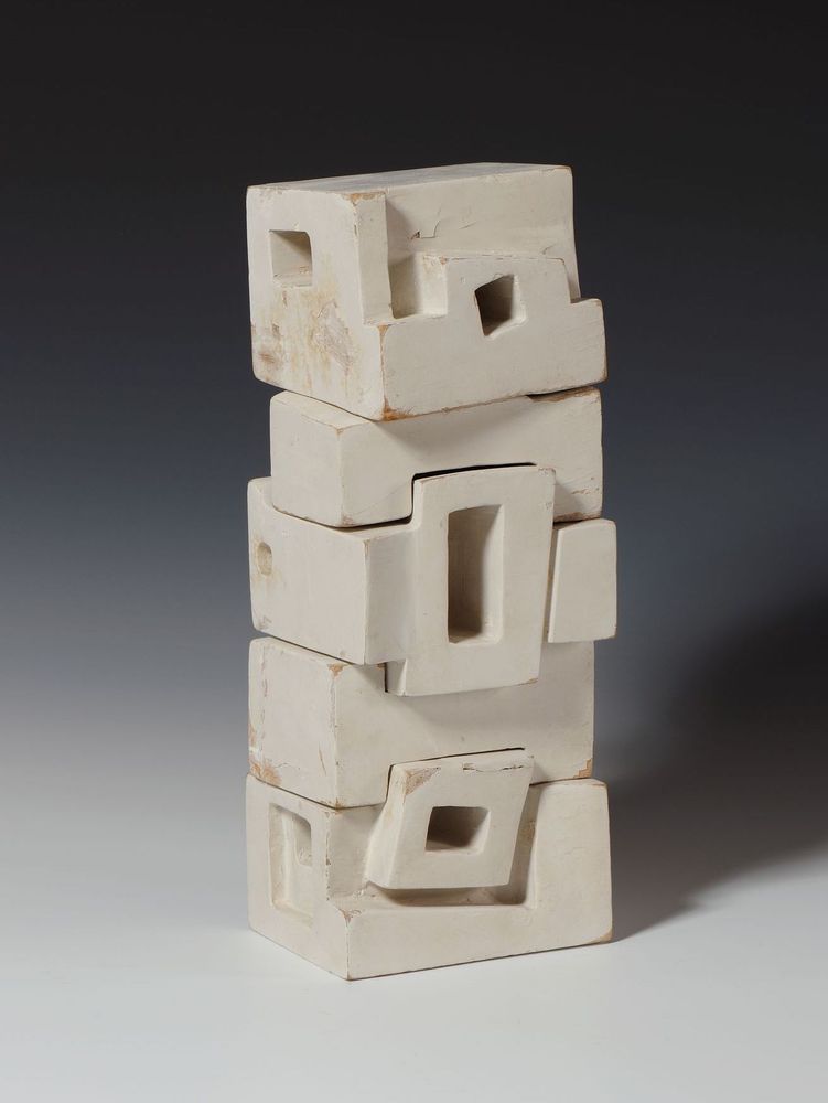 Abstract sculpture in painted white wood, made of stacked block forms with recessed rectangles.