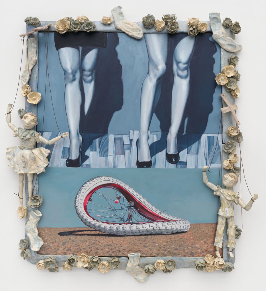 Painting of two women's legs in black heels painted in a soft blue palette. Below their feet is a painting of a bent white and pink bicycle wheel. The canvas is surrounded by small, pale yellow and green ceramic pieces including socks, flowers, and two marionettes.