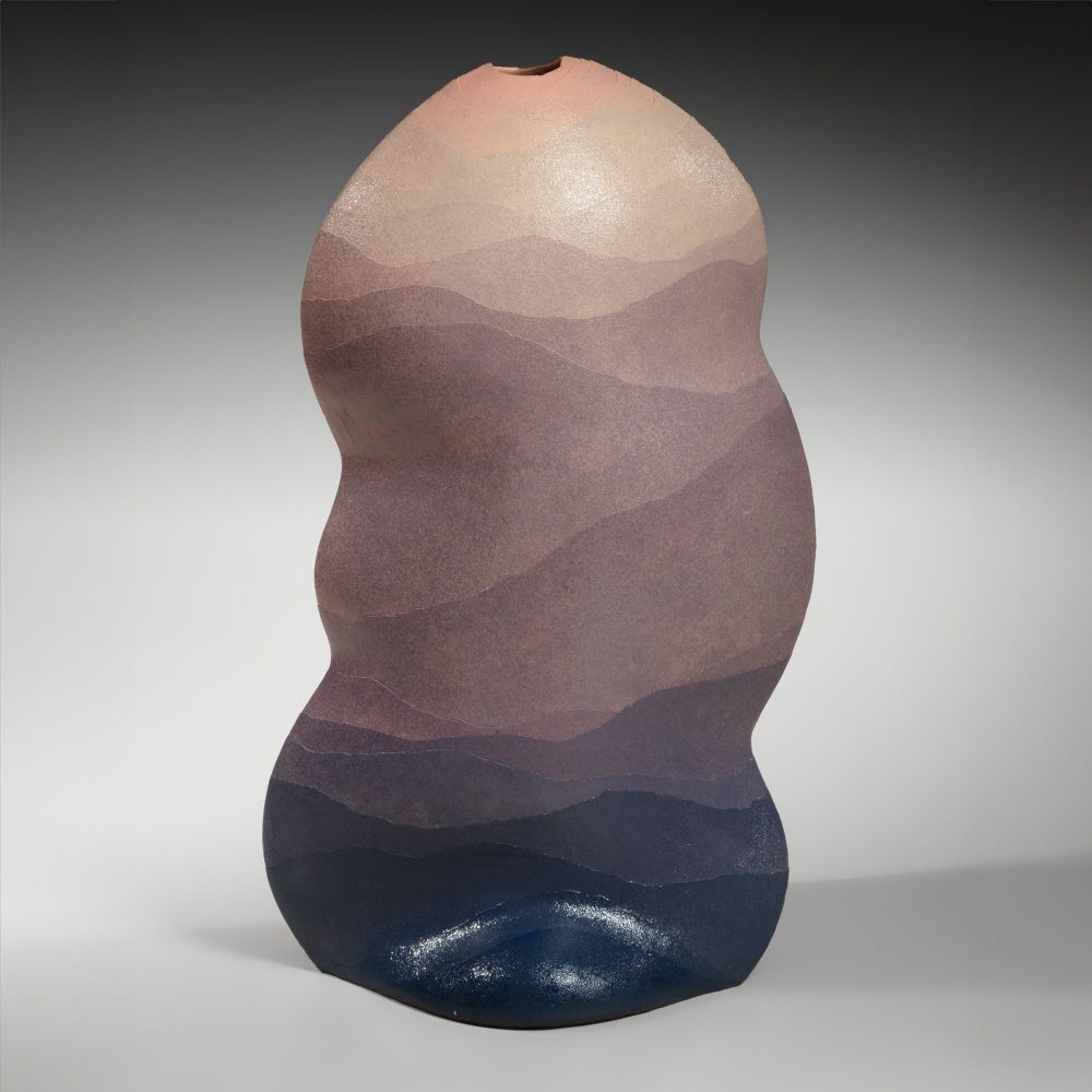 Tall ceramic vessel with wavy curved sides and layers of colored clay forming a gradient moving from deep blue on the bottom up to purple and mauve.