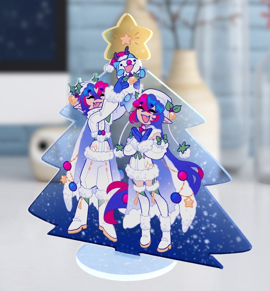 Mock up image of an acrylic standee featuring male and female Alear in their Christmas alts from Fire Emblem heroes. Male Alear is holding up Sommie in the air while female Alear claps with joy