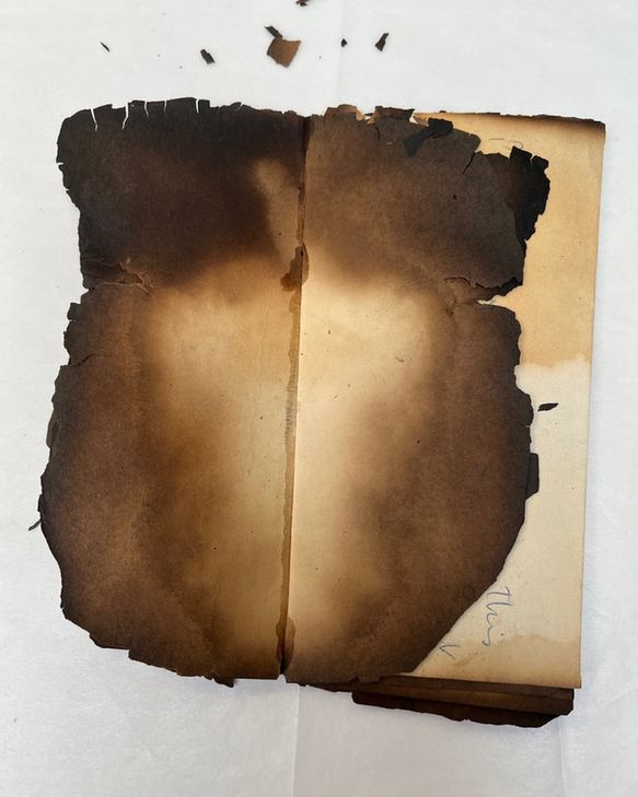 Carefully unfolding one of the burnt pages