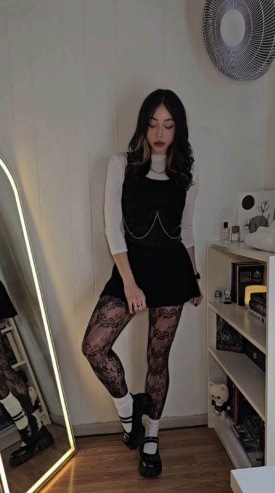Posing in a white turtle neck, black dress, fishnets, white socks and platform mary jane shoes