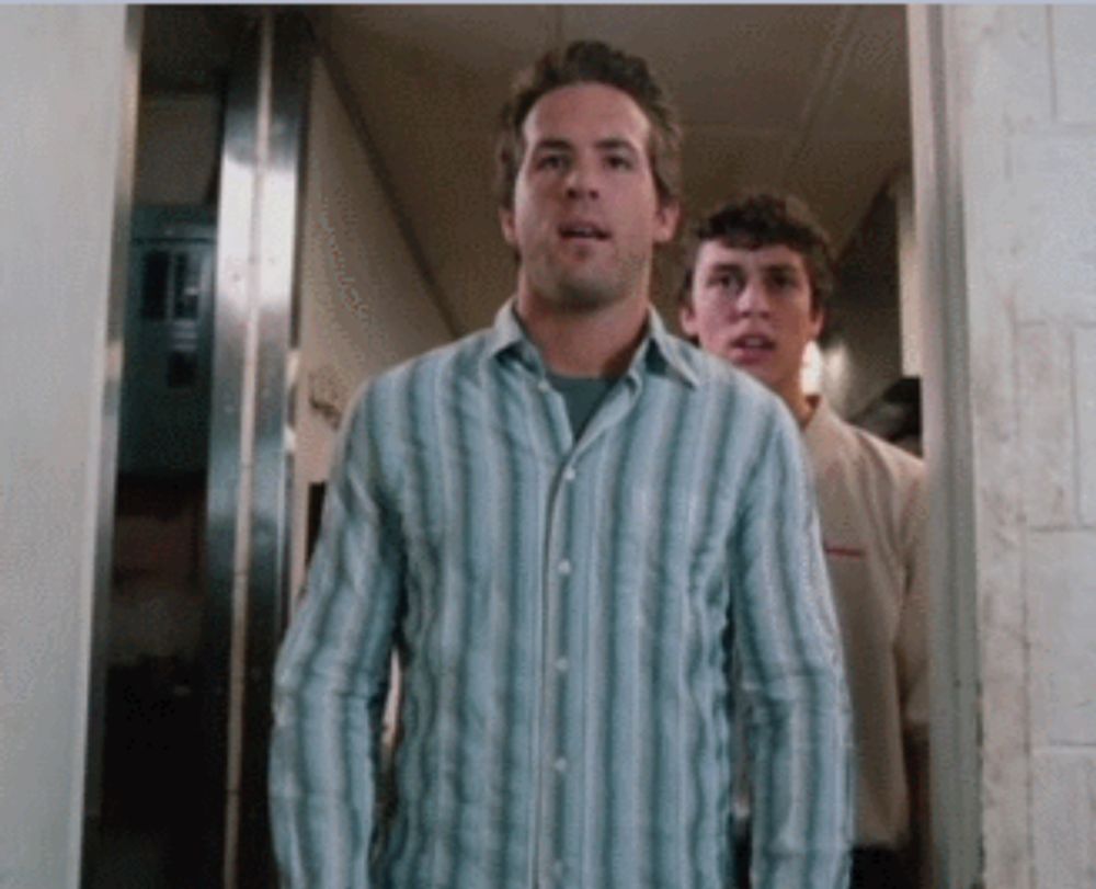 a man in a blue striped shirt stands in a hallway