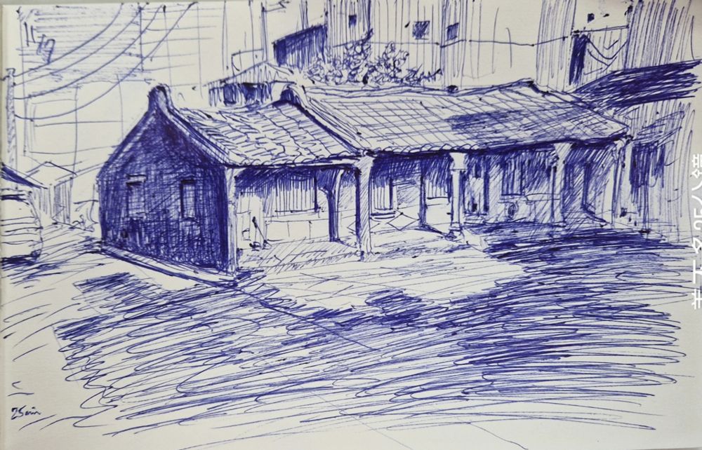This is a biro sketch. A low house with a broken roof is in the partial shadow of a courtyard. It is surrounded by high rise buildings. It is an old fashioned house with roof tiles. The pen strokes are very long and strong for the ground, and and short and soft for the house. Behind and to the top of the house are some leafy branches. The time of the day is mid-morning.