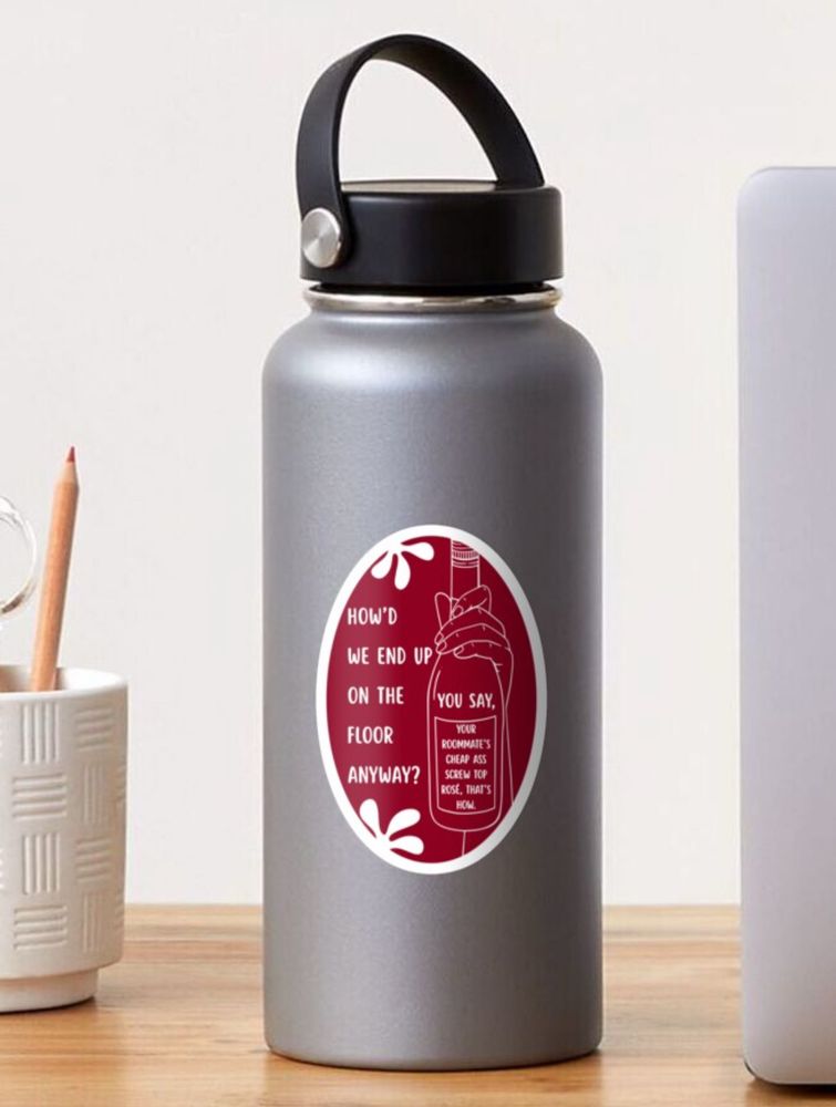 A maroon-colored sticker with an outline of a hand holding a bottle of wine. The text reads “How’d we end up on the floor anyway? You say, your roommate’s cheap ass screw top rosé, that’s how.” displayed on a gray water bottle 