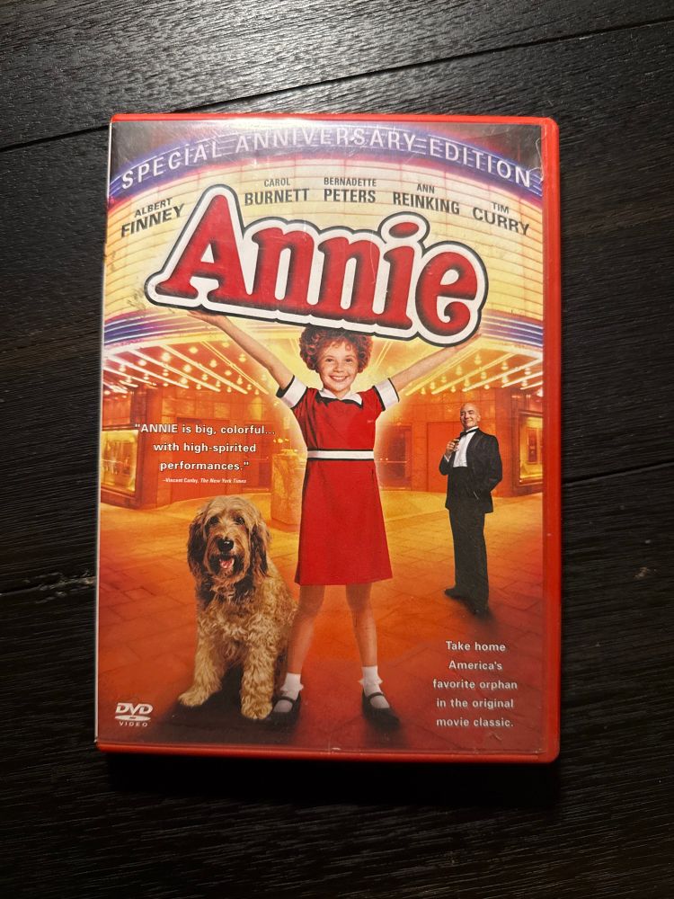 A photo of a special anniversary edition DVD case (Annie 1982 film)

The front of the DVD depicts orphan annie in her iconic red dress, white socks, and black shoes, with her dog sandy and daddy warbucks standing in the background