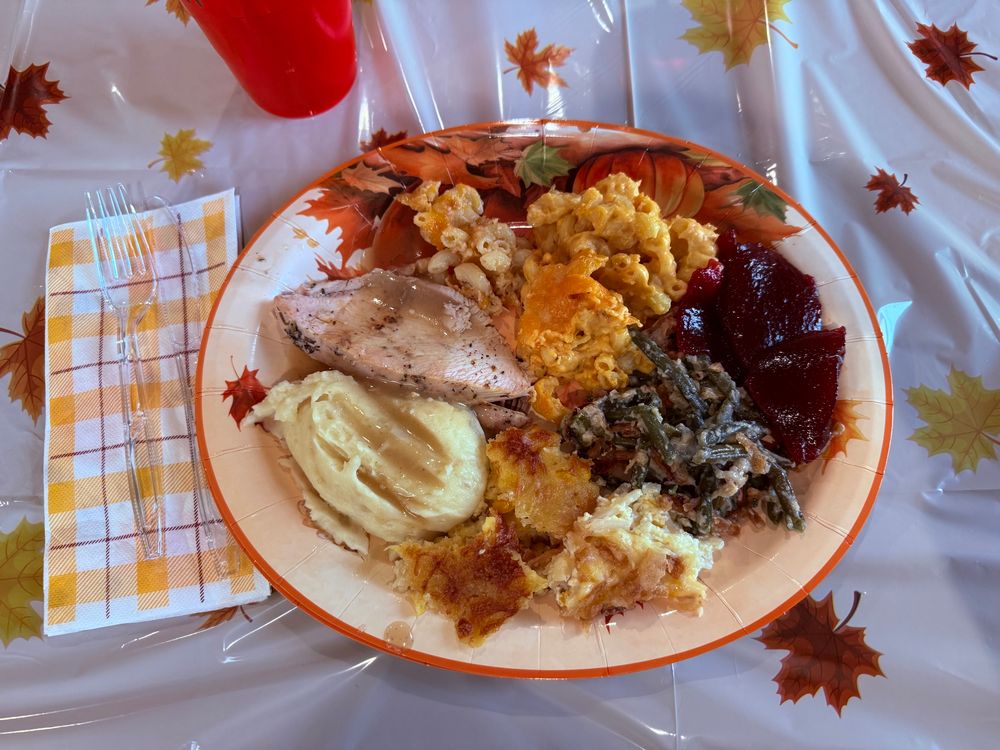 A photo of my it’s giving thanks plate, turkey and gravy, mashed potatoes, corn bread casserole, green bean casserole, cranberry sauce, Mac and cheese 