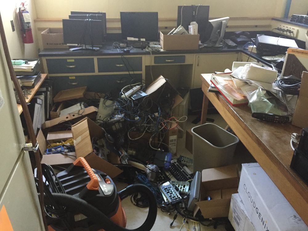 A wet vac, and a huge pile of computer parts, computers, cat5e in various strands, and five monitors. Fridge left