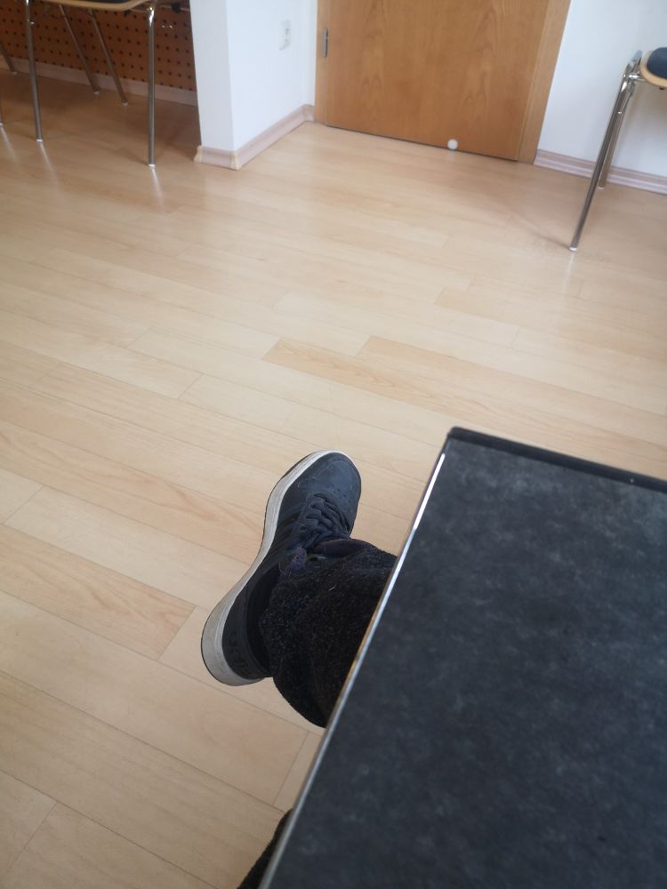 Heller parkettboden und ein Ordner, der auf meinem schoß liegt.